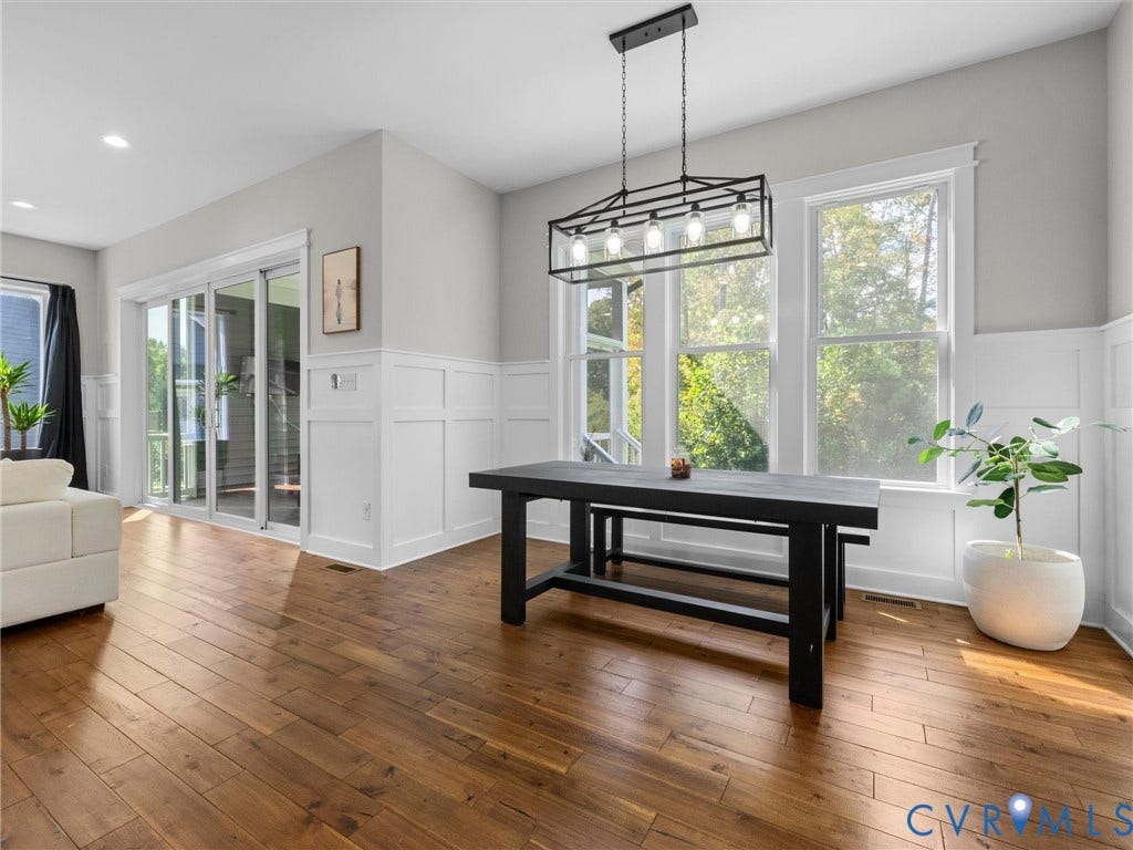 Hardwood flooring, recessed lighting, sliding glass door, wainscoting, and a linear chandelier