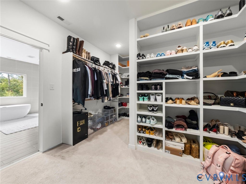 Expansive closet featuring extensive built-in shelving, hanging storage, and carpet flooring