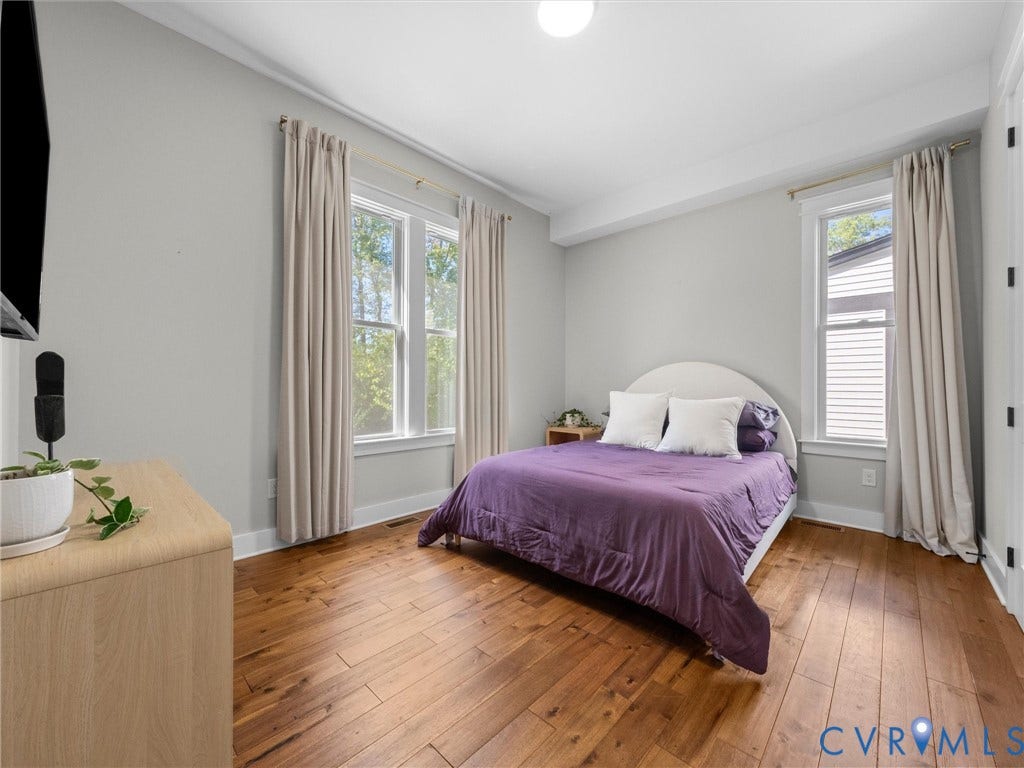 Wood-finish flooring, two large windows, and a flush-mount ceiling light fixture