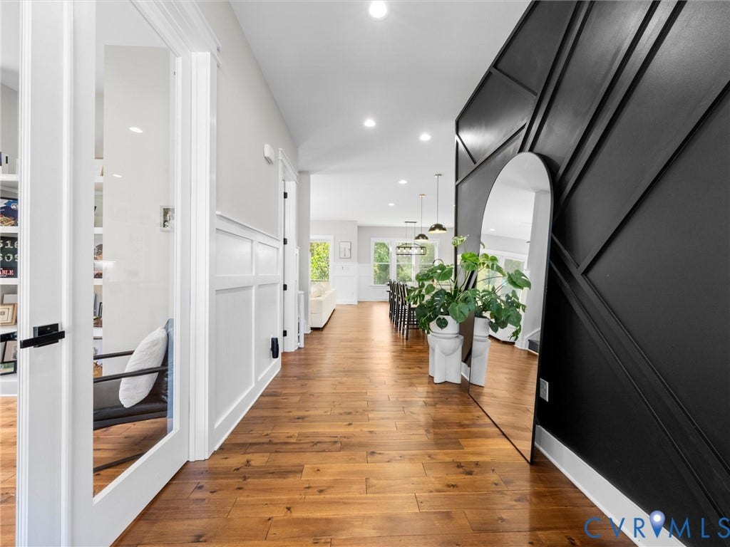 Wood-finish flooring, recessed lighting, wainscoting paneling, and a geometric accent wall