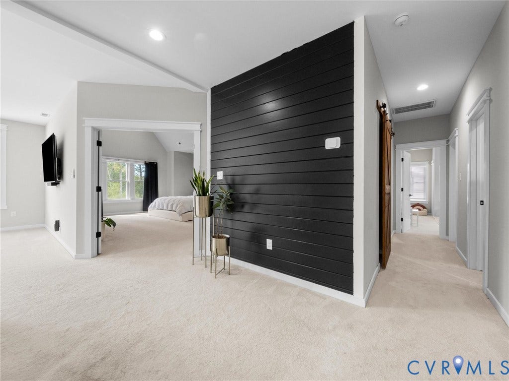 Carpeted hallway featuring a shiplap accent wall, recessed lighting, and a wooden barn door