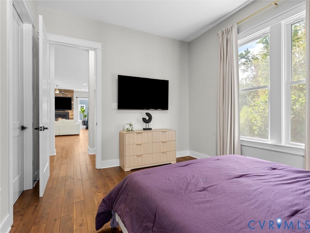 Hardwood flooring throughout, white trim, and a window with exterior views