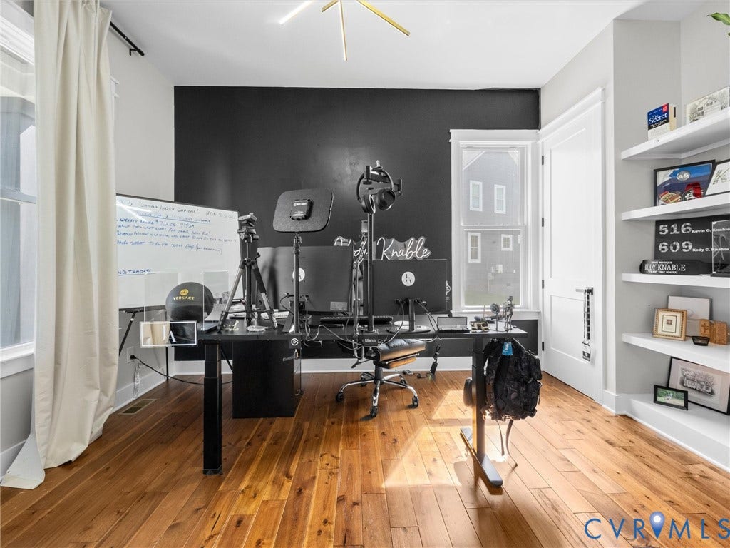 Hardwood flooring, built-in shelving, two windows, and a dark accent wall