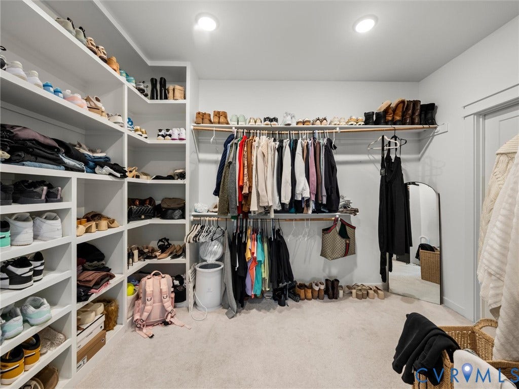 Built-in shelving, multiple hanging rods, recessed lighting, and soft carpet flooring
