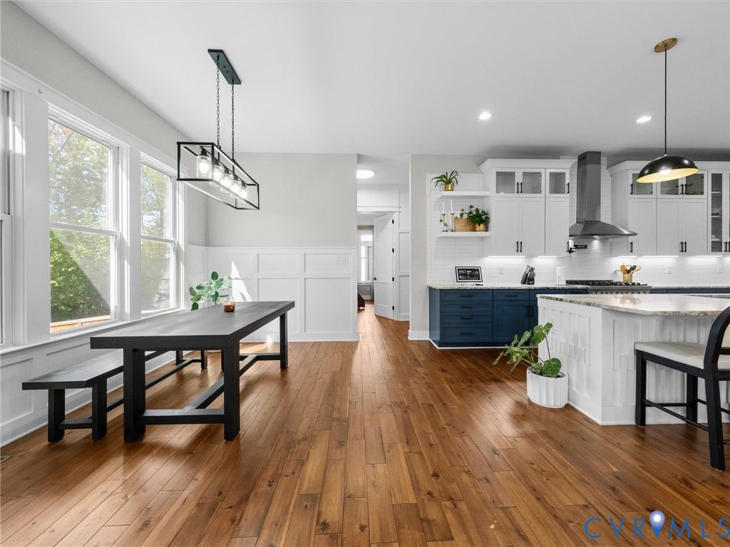 Hardwood-style flooring throughout, kitchen featuring white and blue cabinetry, white subway tile backsplash, and a kitchen island with a light-colored countertop