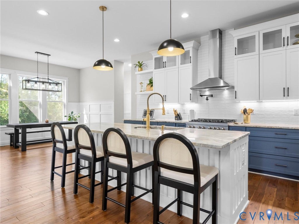 Open-concept kitchen featuring an oversized island with seating, a professional-grade range, stainless steel vent hood, and wood-finish flooring