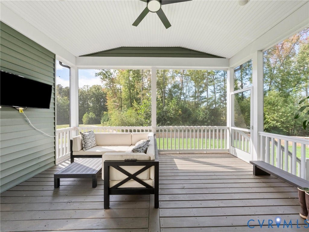Screened porch featuring a ceiling fan, white railings, and wood-finish flooring