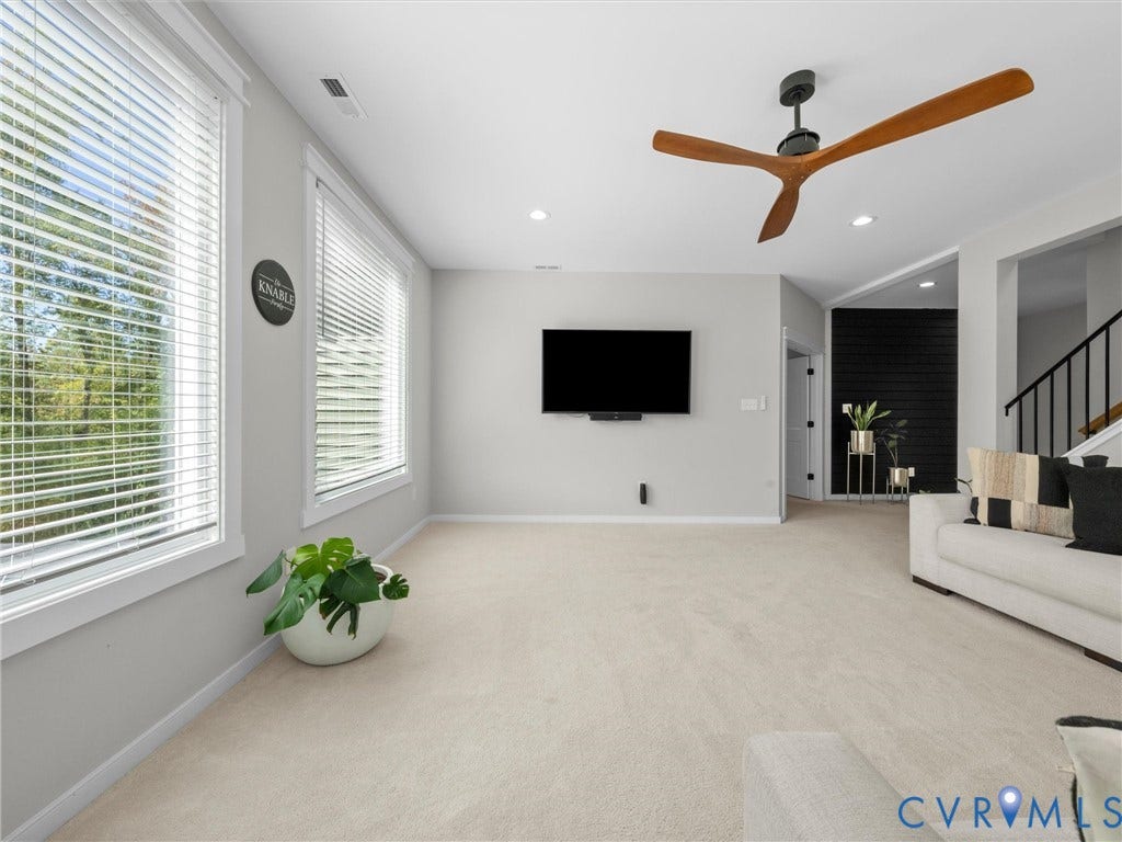 Recessed lighting, wood-finish ceiling fan, wall-mounted television, and carpeted flooring