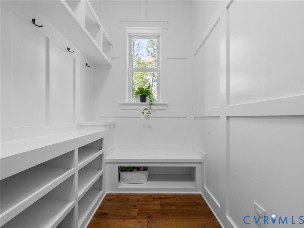 Built-in shelving with storage cubbies and coat hooks, board and batten wall paneling, bench seating, and wood-finish flooring
