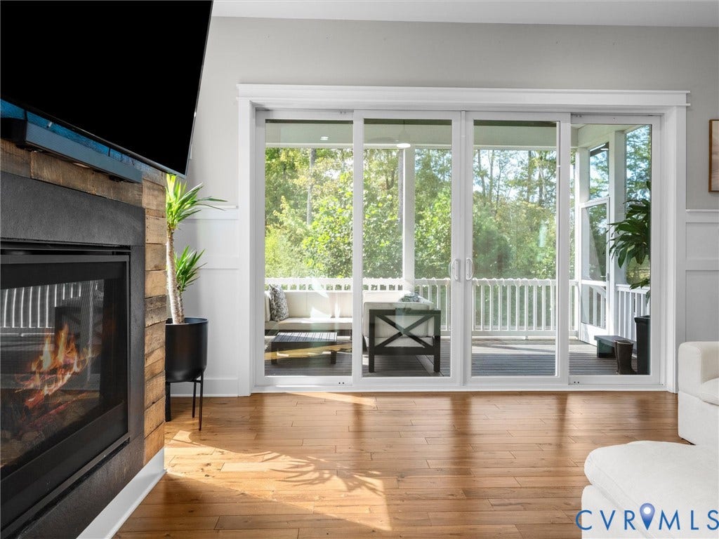Wood-finish flooring throughout the room, anchored by a fireplace with a stacked wood-finish surround