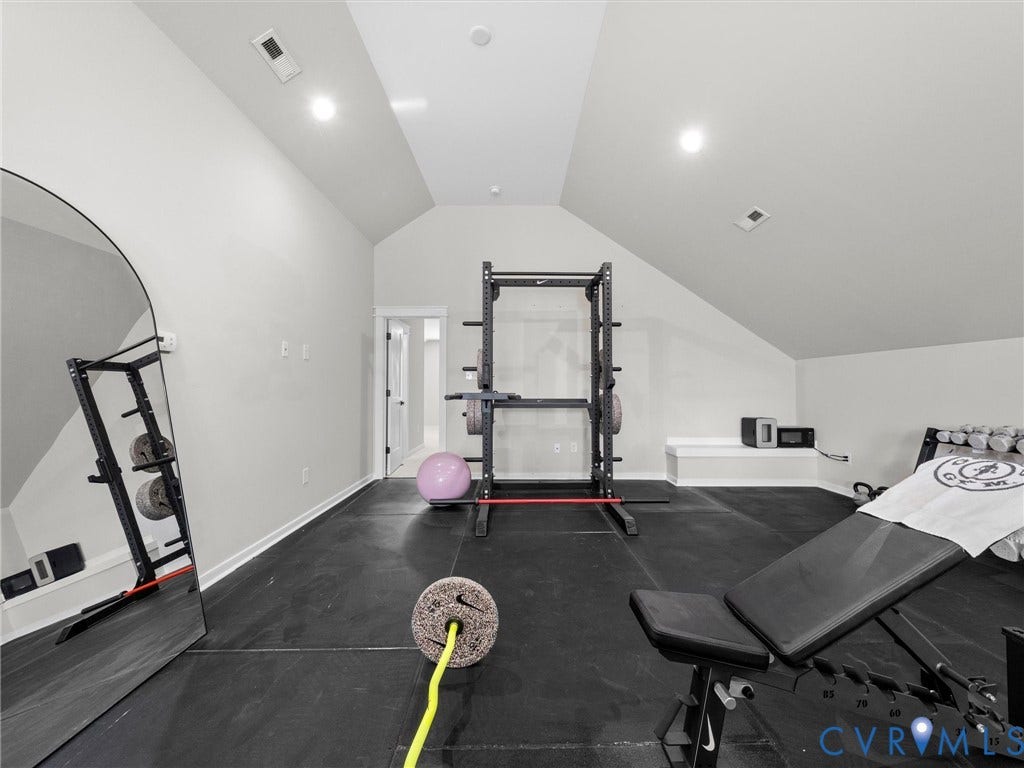 Vaulted ceiling with recessed lighting, rubber flooring, and built-in bench