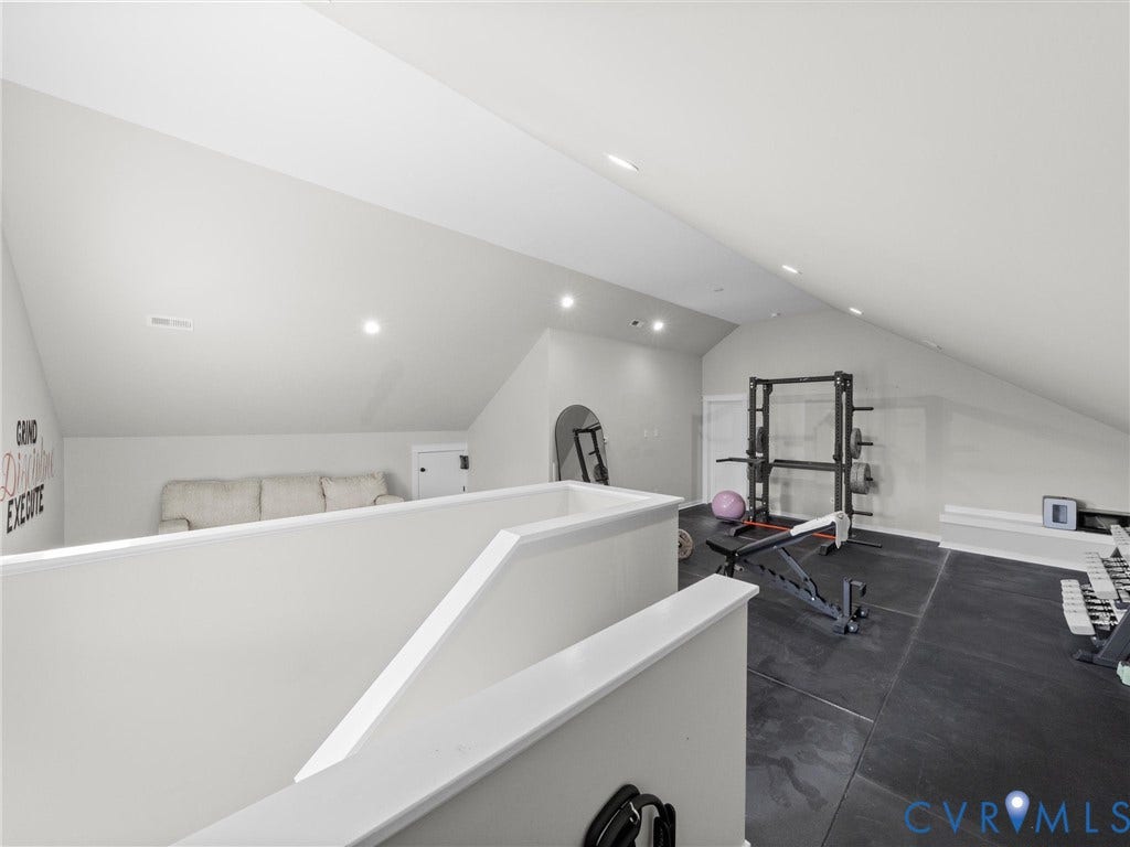 Loft space featuring sloped ceilings, recessed lighting, white walls, and a half-wall partition