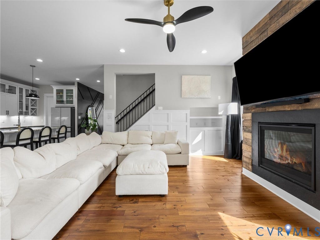 Wood-finish flooring, built-in fireplace with stone-look surround, recessed lighting, ceiling fan, and built-in shelving