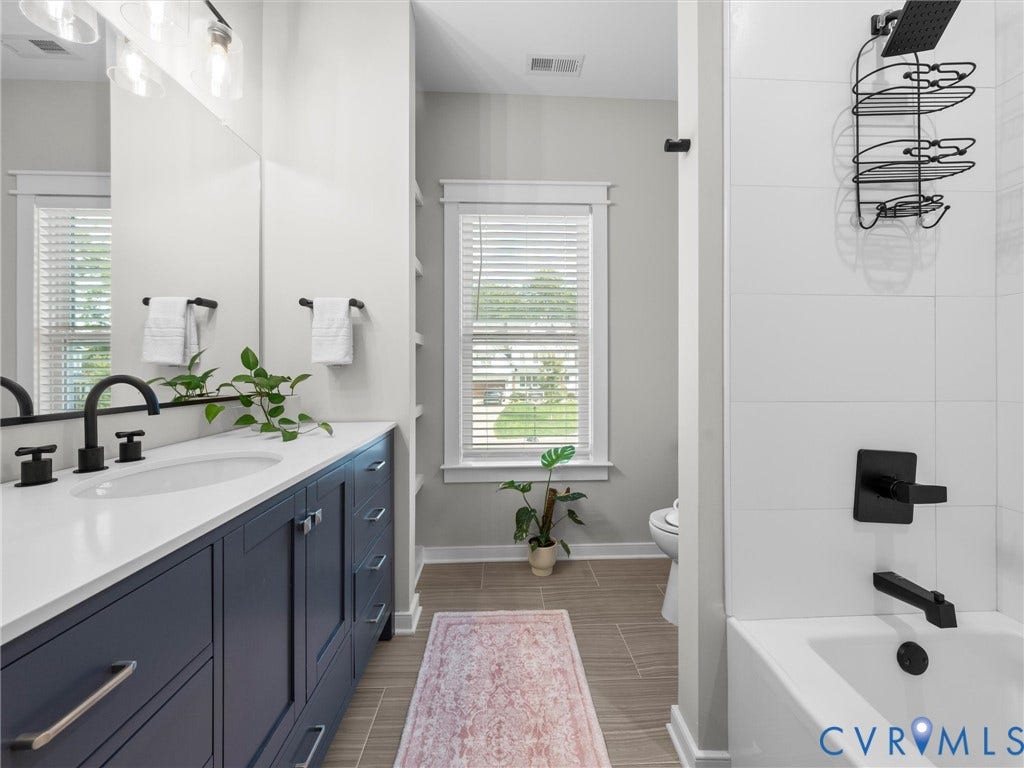 Vanity with a white countertop and undermount sink, dark blue cabinetry, and matte black fixtures