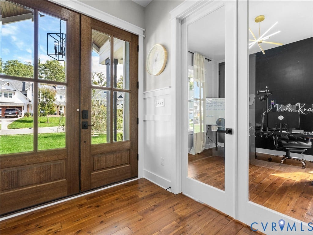 Wood-finish flooring, paneled entry doors with glass inserts, and white wainscoting