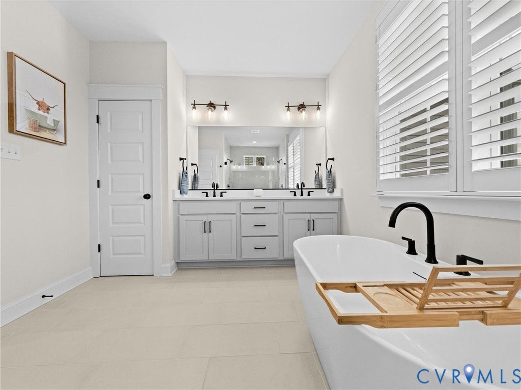 3719 Bellstone Drive, Midlothian, VA 23112 Freestanding soaking tub with matte black fixtures, dual vanity with light gray cabinetry, white plantation shutters, and large format tile flooring