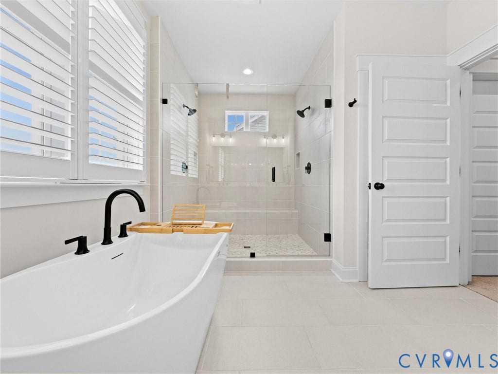 3719 Bellstone Drive, Midlothian, VA 23112 Freestanding soaking tub with matte black fixtures, an expansive walk-in shower with tile surround and glass enclosure, and white plantation shutters