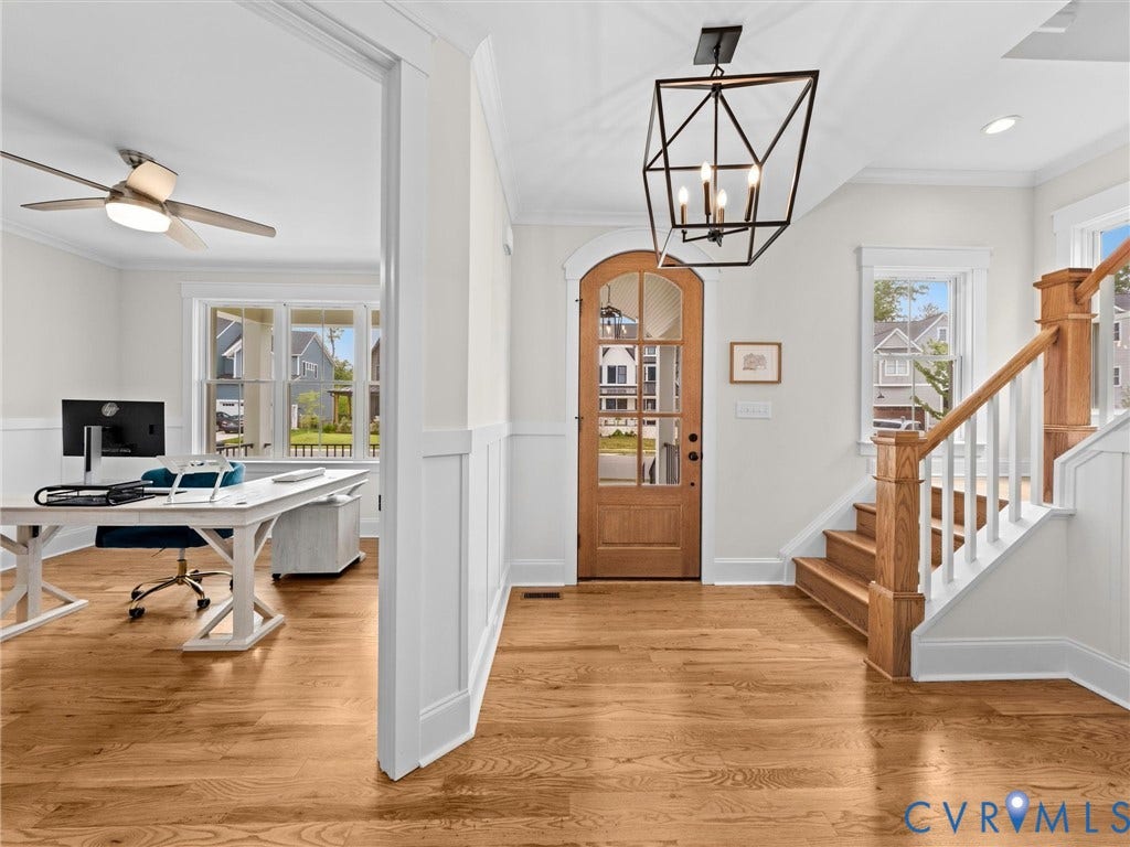 3719 Bellstone Drive, Midlothian, VA 23112 Wood-finish flooring throughout, board and batten wall detailing, natural wood arched-top entry door with glass panels, wood staircase with white risers and balusters, and a black geometric chandelier