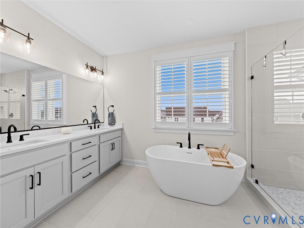 3719 Bellstone Drive, Midlothian, VA 23112 Dual vanity with white countertops, freestanding soaking tub, enclosed shower with glass surround, and white plantation shutters