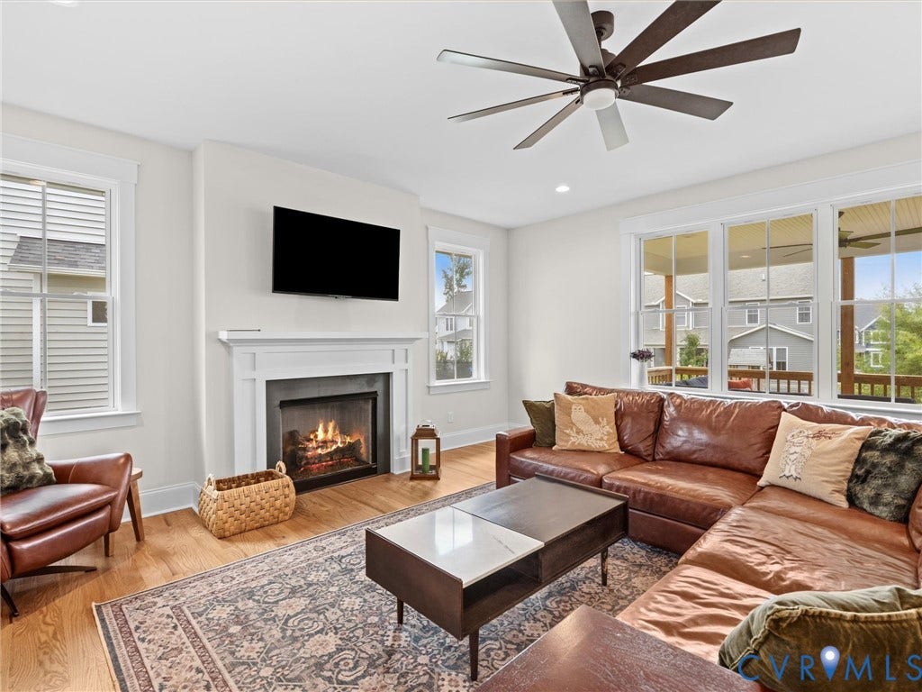 3719 Bellstone Drive, Midlothian, VA 23112 Spacious living area featuring wood-finish flooring, a white mantel fireplace, a ceiling fan, and multiple large windows