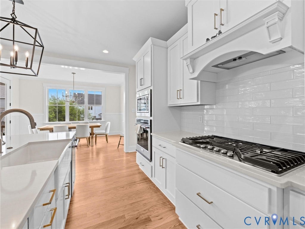 3719 Bellstone Drive, Midlothian, VA 23112 White shaker cabinetry with gold-finish hardware, stainless steel built-in double ovens, gas range, wood-finish flooring, and a white subway tile backsplash