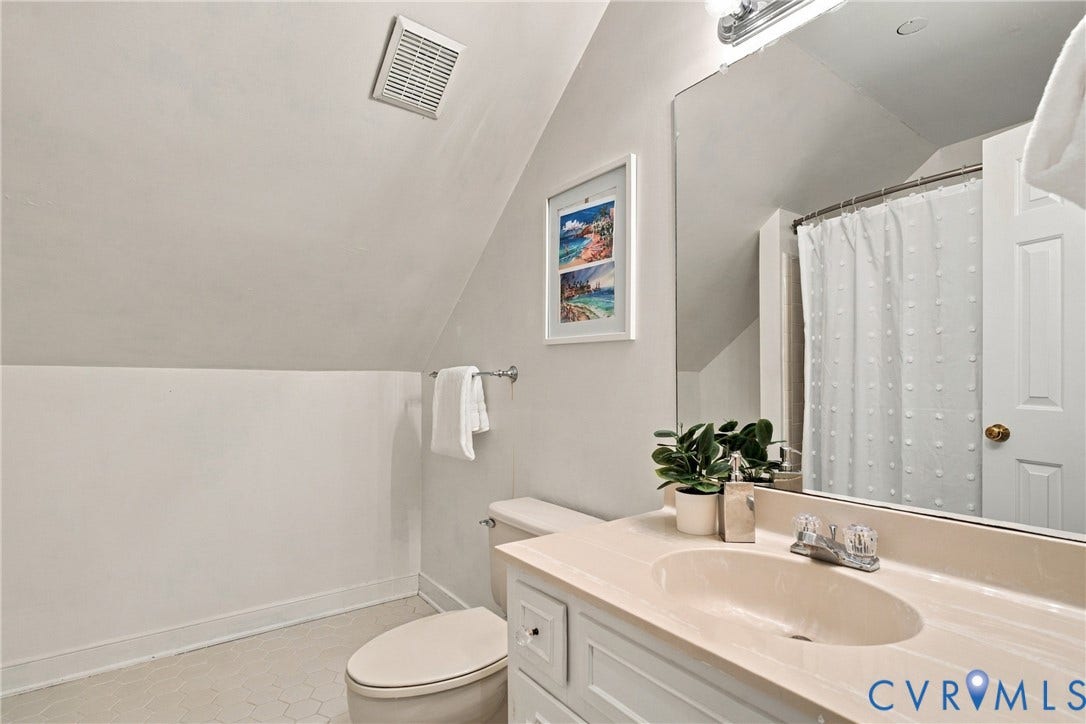 9015 Wood Sorrel Drive, Henrico, VA 23229 Bathroom featuring white vanity cabinetry, integrated sink, large wall-mounted mirror, and tub-shower combination with shower curtain