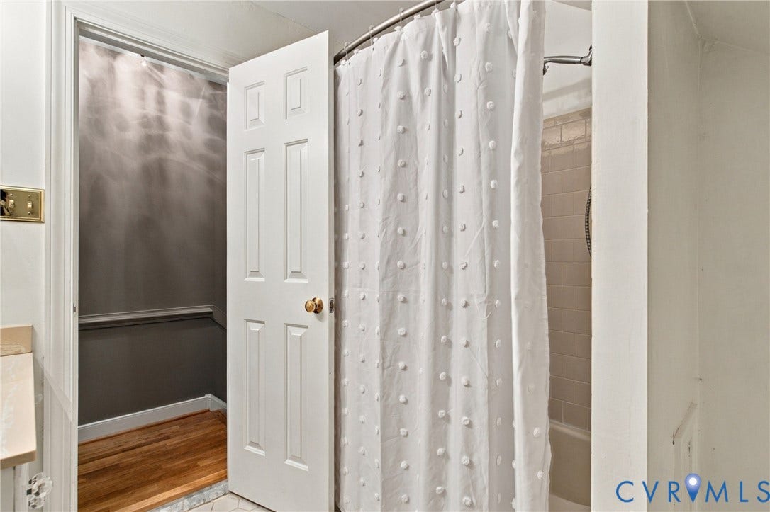 9015 Wood Sorrel Drive, Henrico, VA 23229 Bathroom featuring a tub with tiled surround, six-panel interior door, and wood-finish flooring