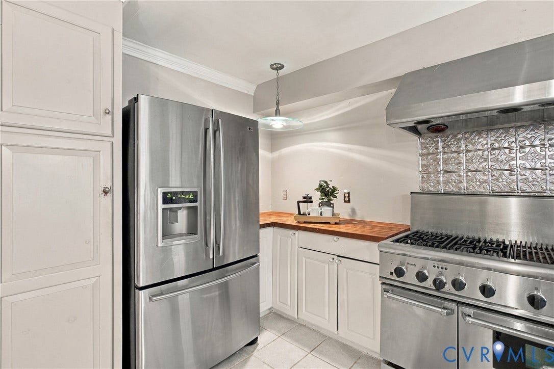 9015 Wood Sorrel Drive, Henrico, VA 23229 Kitchen featuring stainless steel appliances, a multi-burner gas range with professional-style hood, butcher block countertop, decorative metal backsplash, and custom white cabinetry