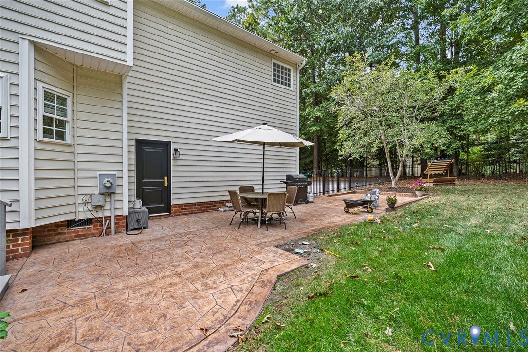 8406 Chandon Court, Chesterfield, VA 23838 Expansive backyard featuring a stamped concrete patio, mature trees, and a wooden play structure