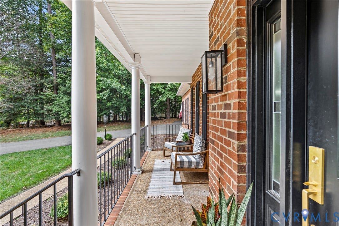 8406 Chandon Court, Chesterfield, VA 23838 Inviting front porch with white columns, black railings, brick exterior, dark entry door with frosted glass, and a modern exterior light fixture