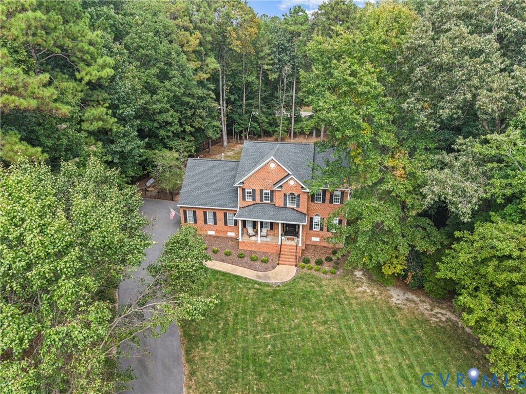 8406 Chandon Court, Chesterfield, VA 23838 Brick exterior residence with a dark shingle roof, surrounded by mature trees, featuring a paved driveway, a manicured lawn, and a covered front porch with steps