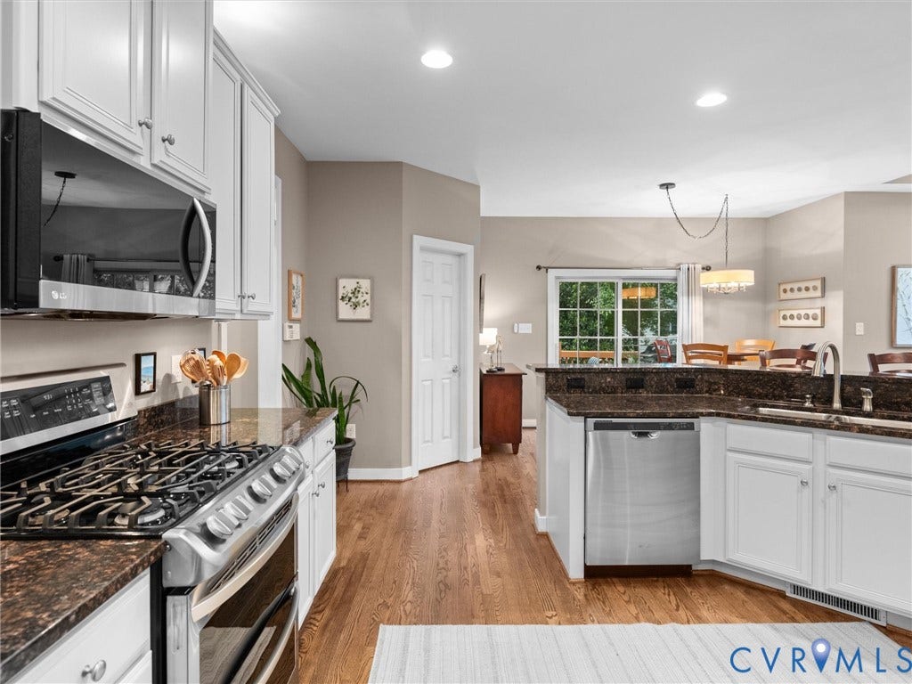 14779 Rolling Spring Drive, Charter Colony, Midlothian, VA 23114 Beautifully renovated in 2023, this bright and inviting kitchen blends timeless style with everyday function. White cabinetry, rich granite countertops, stainless appliances and hardwood floors create a classic look, while the open design flows effortlessly into the breakfast area with views of the lush backyard beyond