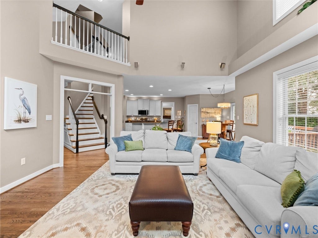 14779 Rolling Spring Drive, Charter Colony, Midlothian, VA 23114 Dramatic two-story family room where soaring ceilings, an open upper gallery and abundant natural light create an incredible sense of space. The open-concept design flows seamlessly into the renovated kitchen and casual dining area, while warm hardwood floors keep this impressive room feeling comfortable and inviting