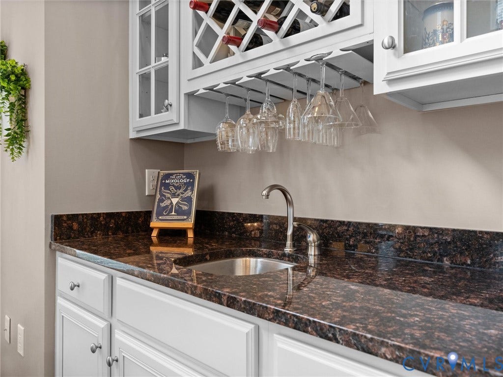 14779 Rolling Spring Drive, Charter Colony, Midlothian, VA 23114 Made for entertainingthe beautifully appointed butlers pantry combines custom cabinetry, granite, a prep sink, wine storage and hanging stemware, adding both function and a touch of sophistication between the homes gathering spaces