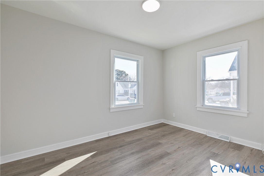 1305 Overlook Street, Richmond, VA 23224 Neutral wall color, wood-finish flooring, two large windows, white window trim, and a ceiling-mounted light fixture