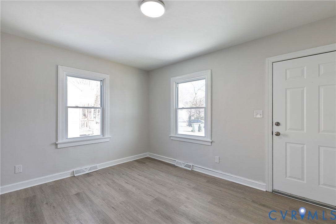 1305 Overlook Street, Richmond, VA 23224 Light gray wall paint with two windows, wood-finish flooring, and a flush mount ceiling light fixture