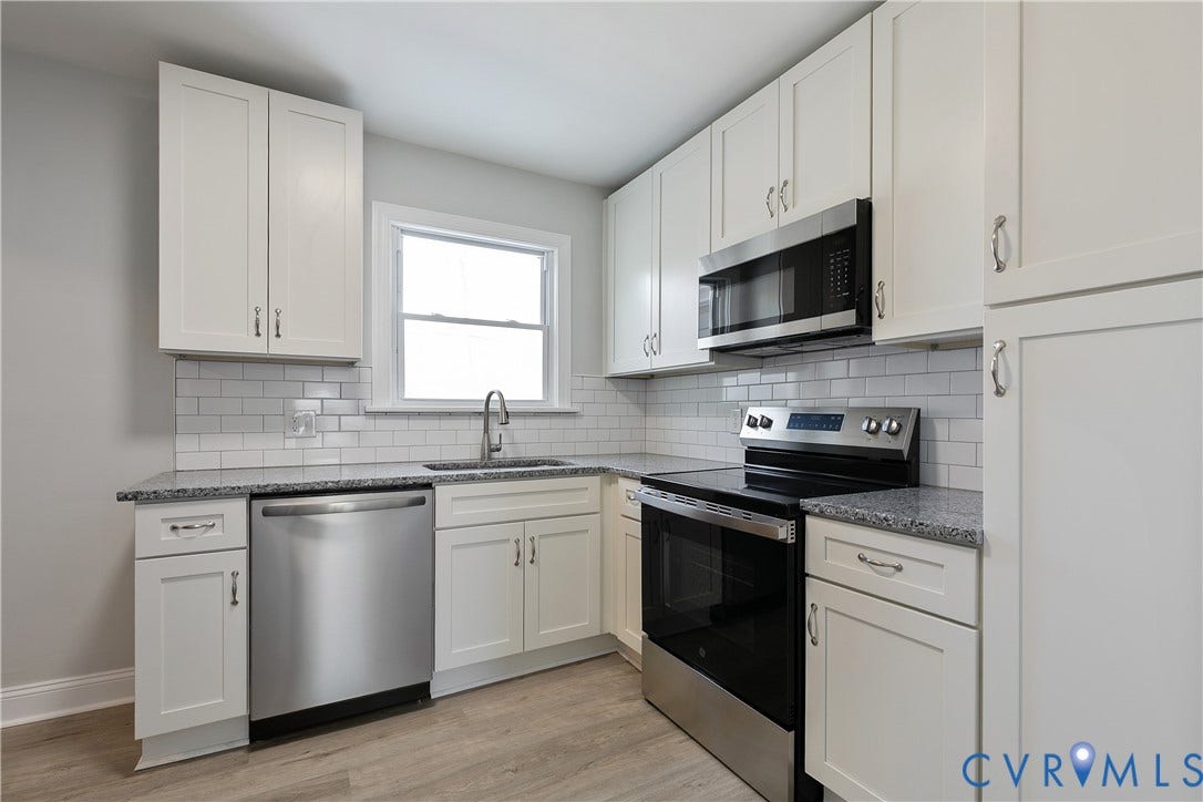1305 Overlook Street, Richmond, VA 23224 White shaker cabinetry, stainless steel appliances, subway tile backsplash, speckled countertops, and wood-finish flooring