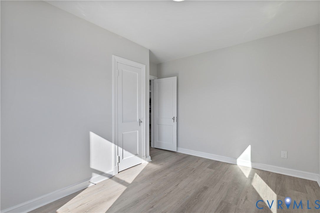 1305 Overlook Street, Richmond, VA 23224 Light wood-finish flooring with white trim, bright white walls, and a white paneled door
