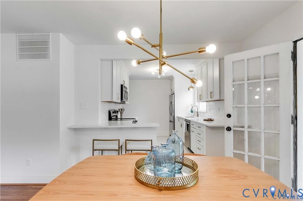 2304 Buckingham Avenue, Henrico, VA 23228 Kitchen featuring white cabinetry, light countertops, and a modern brass chandelier