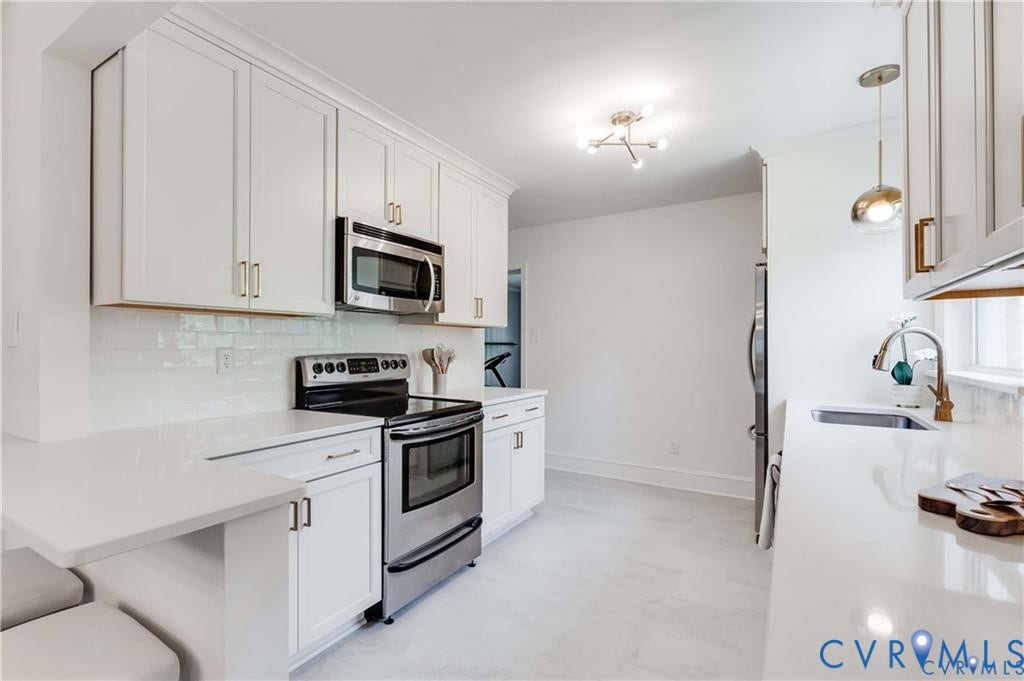 2304 Buckingham Avenue, Henrico, VA 23228 White shaker cabinetry, stainless steel appliances, quartz countertops, white subway tile backsplash, and light-toned flooring