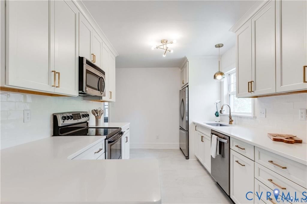 2304 Buckingham Avenue, Henrico, VA 23228 White cabinetry with gold-tone hardware, stainless steel appliances, white subway tile backsplash, and light-toned countertops