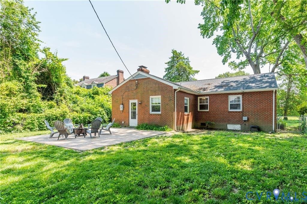 2304 Buckingham Avenue, Henrico, VA 23228 Brick exterior construction featuring a rear patio, mature trees, and a grassy yard area