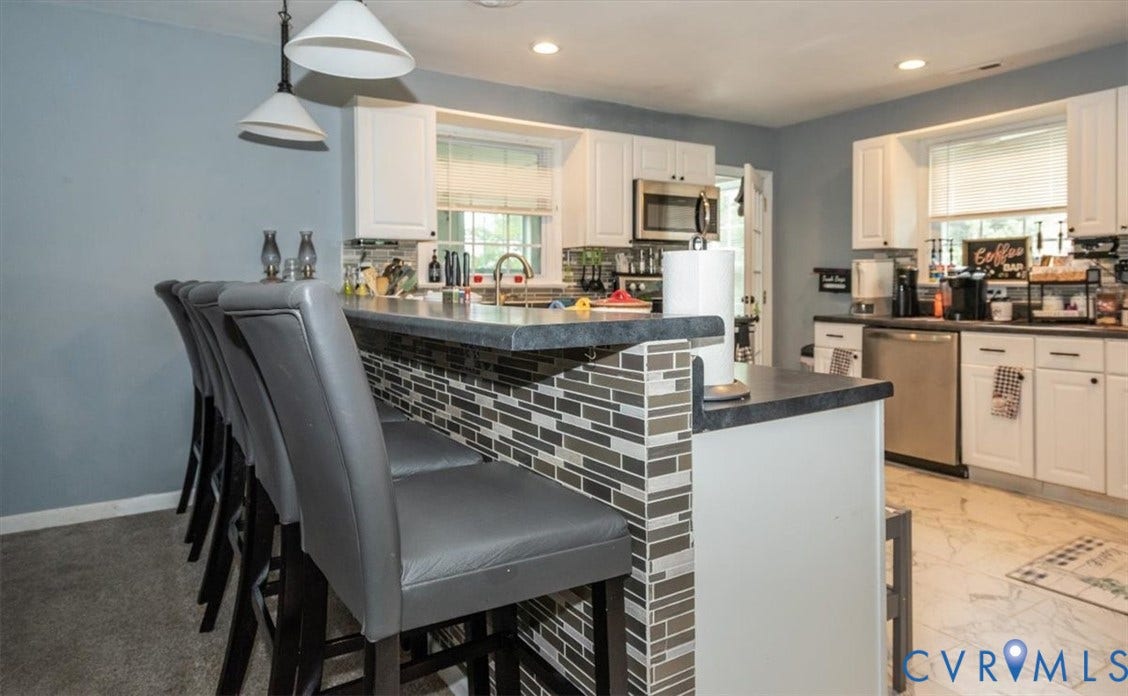5510 Alberta Road, Stanwick, Midlothian, VA 23832 Kitchen featuring white cabinetry, stainless steel appliances, a tile backsplash, and a breakfast bar with a tile accent wall