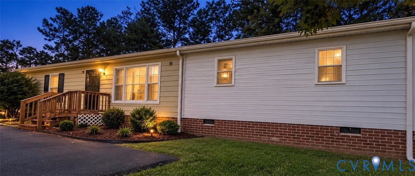 Siding exterior with a brick foundation accent, wood-finish deck, and surrounding landscaping