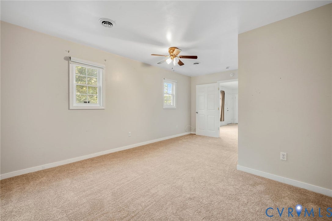 Carpeted flooring, recessed lighting, ceiling fan, two windows, and a doorway with a panel door