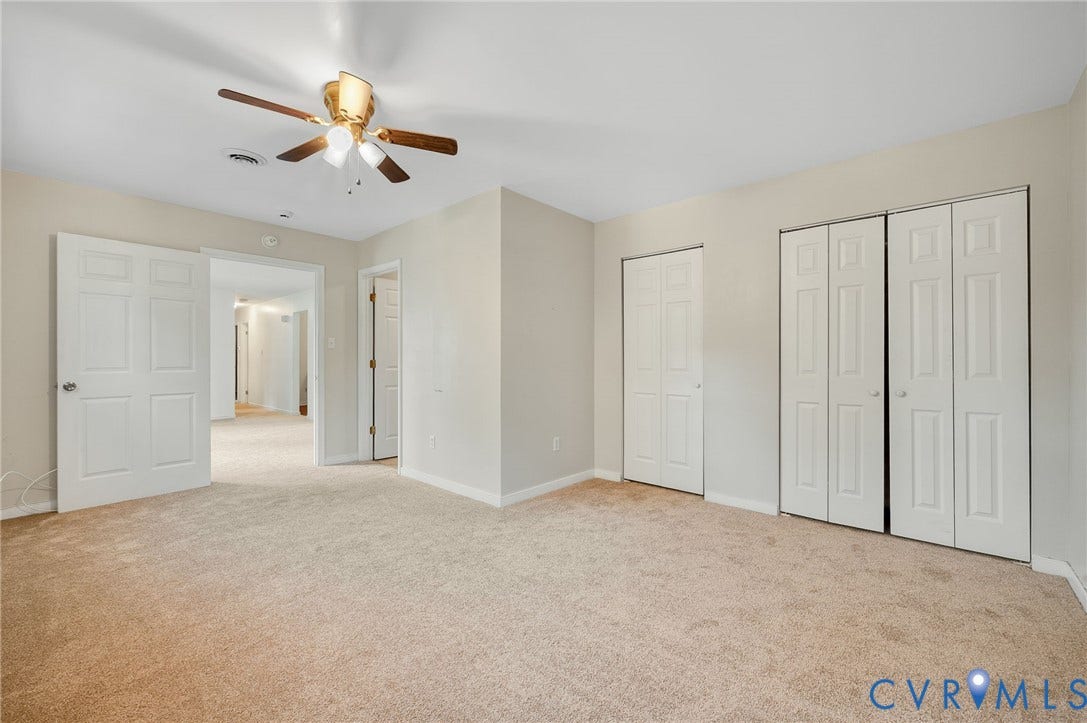 Carpeted flooring, neutral wall tones, ceiling fan with light fixture, and multiple bi-fold door closets