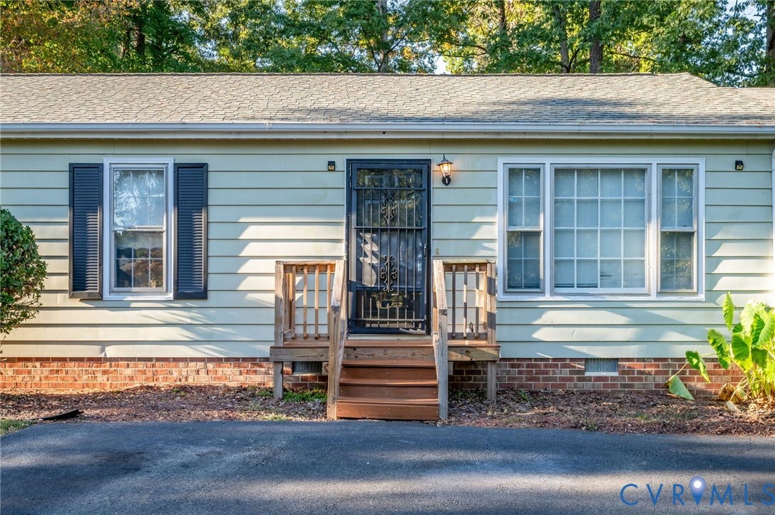 Light-colored siding exterior featuring a security screen door, exterior wall lighting, and a small wooden porch