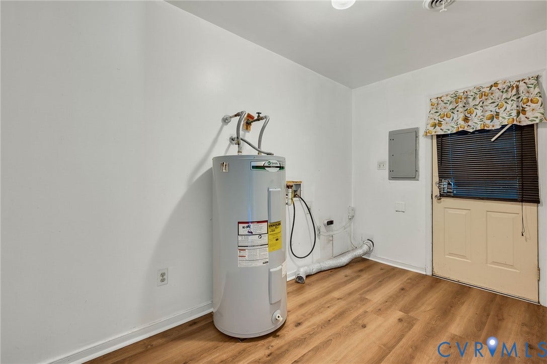 Utility room featuring wood-finish flooring and a white paneled door