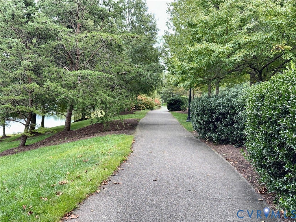 3900 Liesfeld Place, Glen Allen, VA 23060 Paved pathway bordered by mature trees and manicured hedges, with a glimpse of a water feature