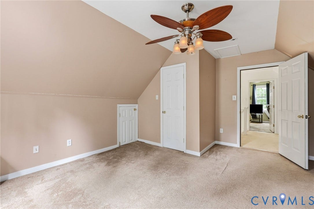Sloped ceiling with neutral wall paint, carpeted flooring, and a ceiling fan with integrated lighting